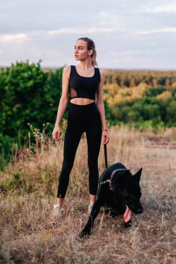 Gün batımında genç ve narin bir kız çoban köpeğiyle oynuyor.