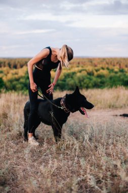 Gün batımında genç ve narin bir kız çoban köpeğiyle oynuyor.