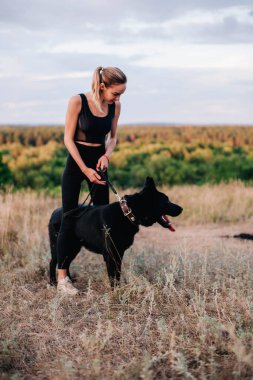 Gün batımında genç ve narin bir kız çoban köpeğiyle oynuyor.