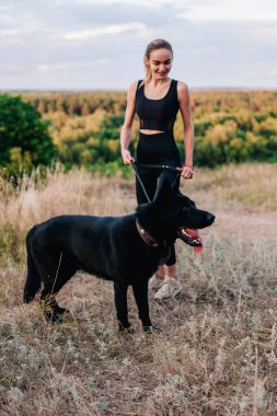 Gün batımında genç ve narin bir kız çoban köpeğiyle oynuyor.