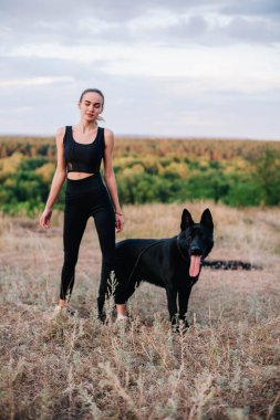 Gün batımında genç ve narin bir kız çoban köpeğiyle oynuyor.