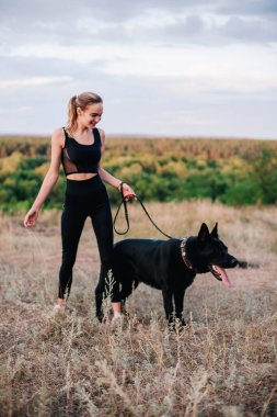 Gün batımında genç ve narin bir kız çoban köpeğiyle oynuyor.