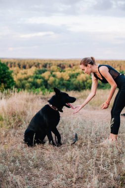 Gün batımında genç ve narin bir kız çoban köpeğiyle oynuyor.