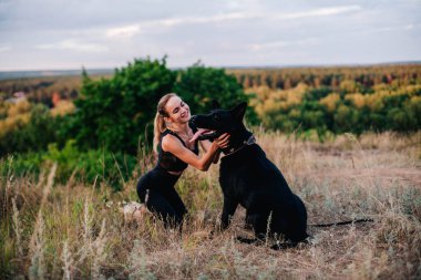 Gün batımında genç ve narin bir kız çoban köpeğiyle oynuyor.