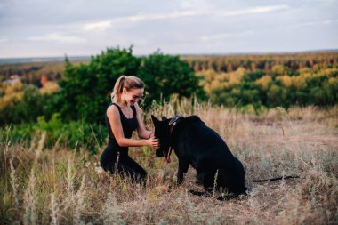 Gün batımında genç ve narin bir kız çoban köpeğiyle oynuyor.