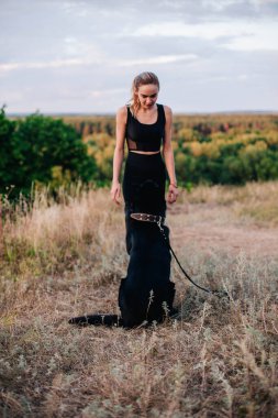 Gün batımında genç ve narin bir kız çoban köpeğiyle oynuyor.