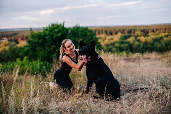 Gün batımında genç ve narin bir kız çoban köpeğiyle oynuyor.