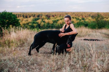Gün batımında genç ve narin bir kız çoban köpeğiyle oynuyor.