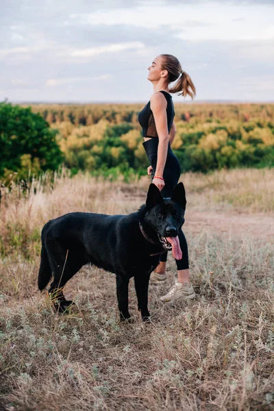 Gün batımında genç ve narin bir kız çoban köpeğiyle oynuyor.