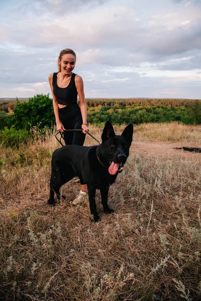 Gün batımında genç ve narin bir kız çoban köpeğiyle oynuyor.