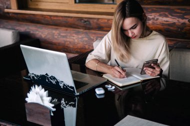 Restoran masasındaki ince kız dizüstü bilgisayarın arkasında çalışıyor.
