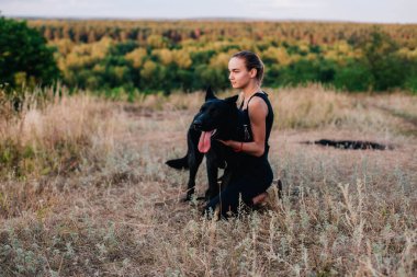 Gün batımında genç ve narin bir kız çoban köpeğiyle oynuyor.