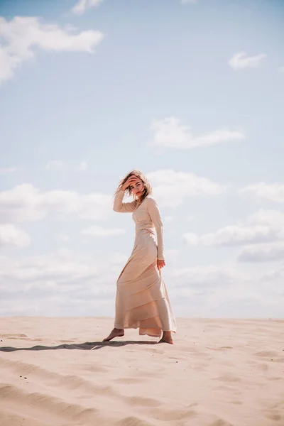 Młoda, szczupła dziewczyna w beżowej sukience spaceruje po pustyni — Zdjęcie stockowe