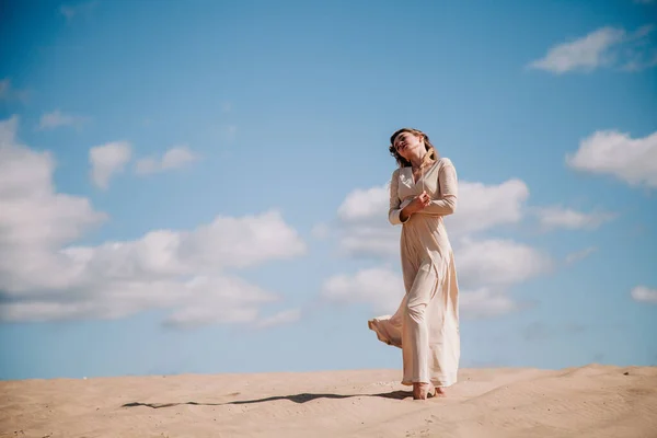 Young, slender girl in beige dress walks in the desert — Stock Photo, Image