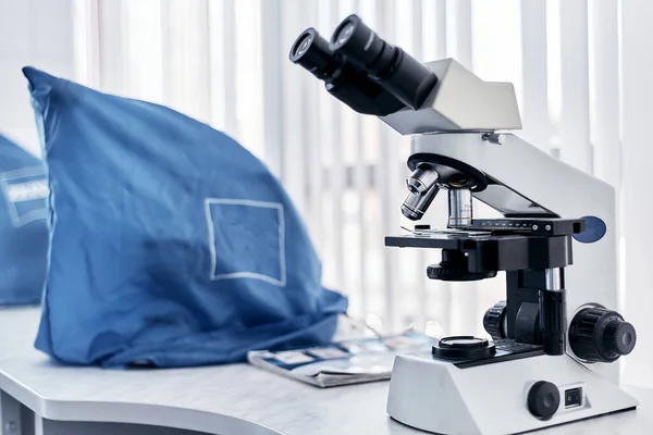 Microscope in the hospital laboratory on the table close-up on a clean white background hospital laboratory, study of biomaterials, blood analysis, research, virus