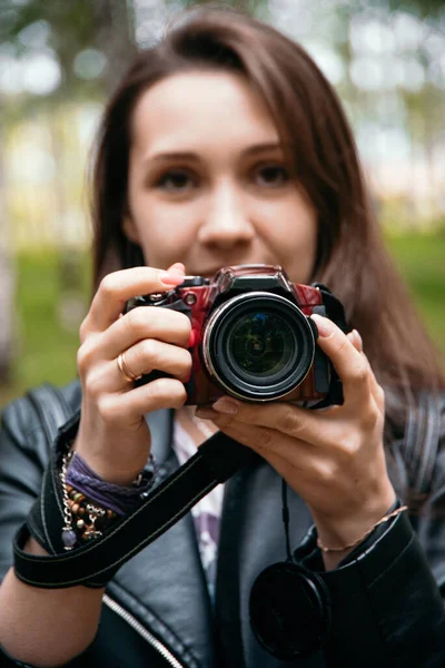 Kamera, fotoğraf ekipmanlarının önünde bir kızın elinde. Fotoğraf hobileri, fotoğrafçılık eğitimi, izole bir şekilde yürüyen vahşi yaşam.