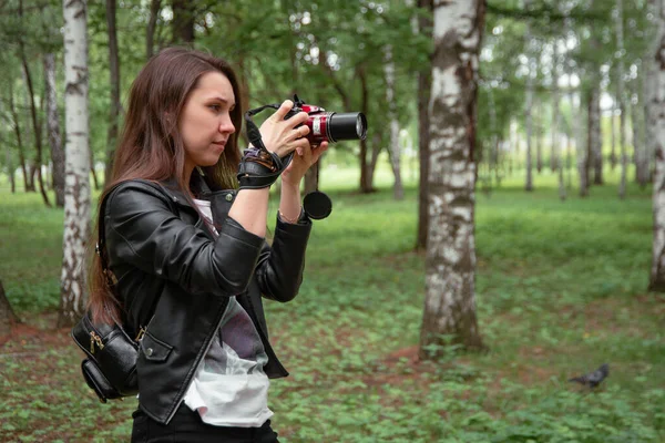 Ormanda bir parkta, doğada bir kamerayla hayvanları fotoğraflayan bir kız.