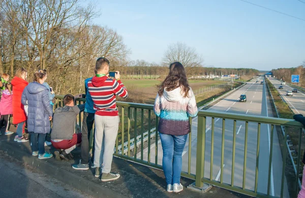Children standing on the bridge above the autobahn and photographing cars — Stock Photo, Image