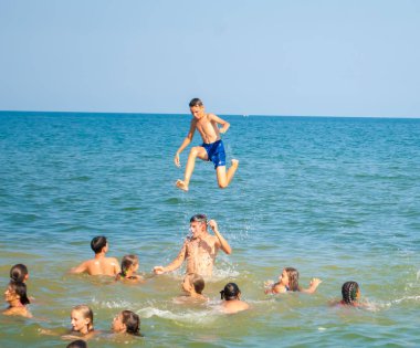 Yaz kampında denizde yüzen çocuklar takla atıyor