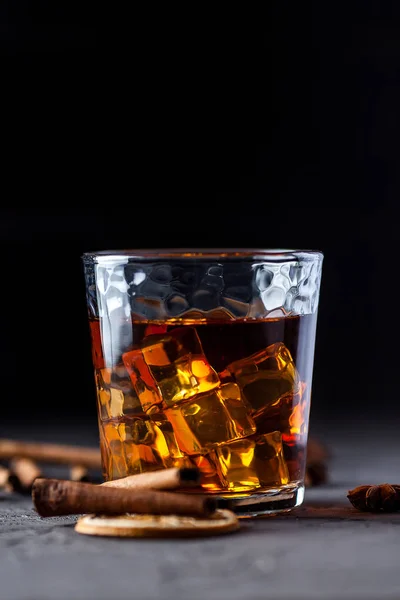 Verre de brandy ou whisky, épices et décorations sur fond sombre — Photo