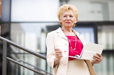 Sarışın iş kadını. Yaşlı bir iş kadını ve tablet, açık kahve.