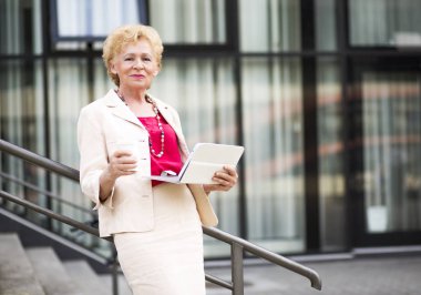 Sarışın iş kadını. Yaşlı bir iş kadını ve tablet, açık kahve.
