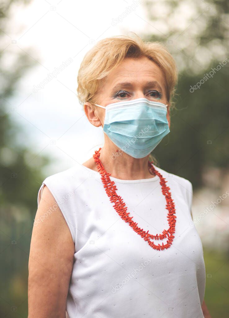 Portrait of a beautiful Blonde Woman Wearing a Mask.Senior woman wearing medical face mask during Covid-19 pandemic, outdoor.