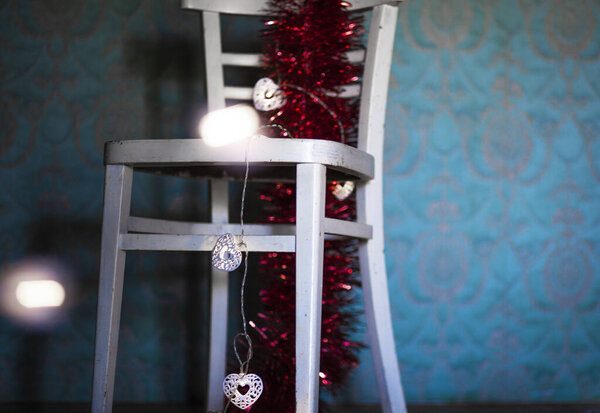 Winter. Christmas decoration on a rustic chair.Christmas ornament, red - gold color,  with shining lamps.