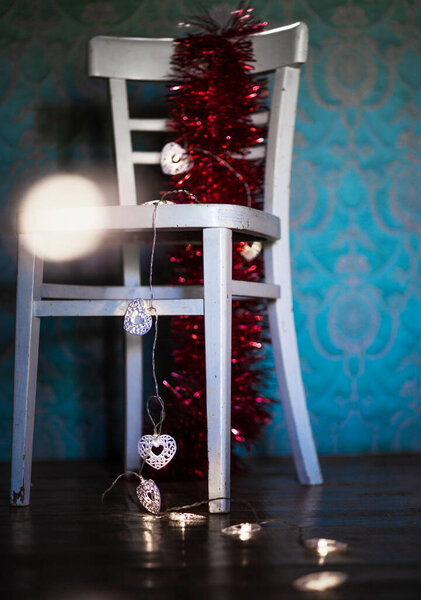 Winter. Christmas decoration on a rustic chair.Christmas ornament, red - gold color,  with shining lamps.