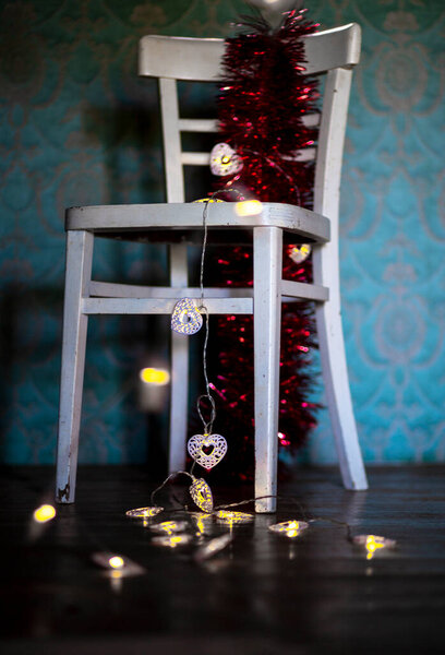 Winter. Christmas decoration on a rustic chair.Christmas ornament, red - gold color,  with shining lamps.