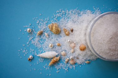 Deniz kabukları ile mavi arka plan üzerinde peeling için deniz tuzu 