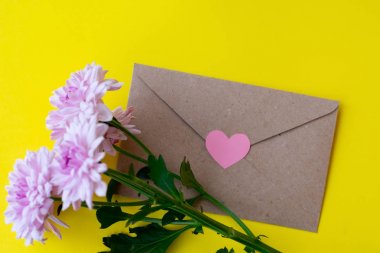 Parlak sarı bacground pembe kalp ile pembe krizantem çiçekleri ile Aşk zarf