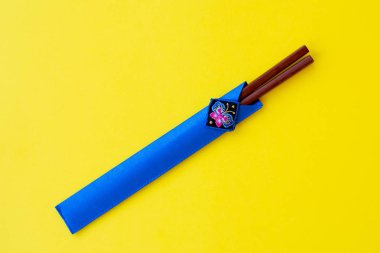 Parlak sarı arka plan üzerinde mavi durumda bambu yapılmış kahverengi ahşap çubuklar