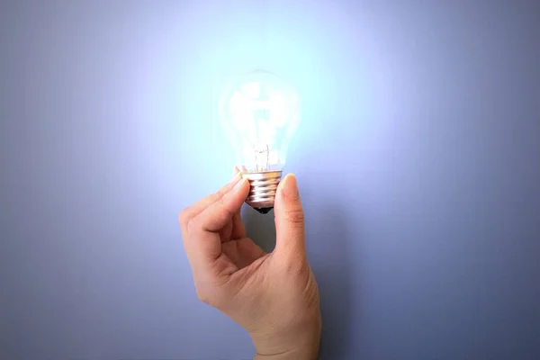 Switched on light bulb on young girl\'s hand. Concept of having idea, creatiivity and knowledge