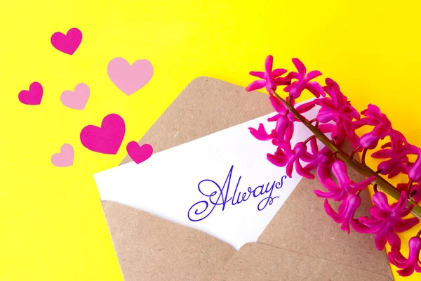 Love envelope and letter with written word always and pink hyacinth flowers with pink hearts on bright yellow bacground.