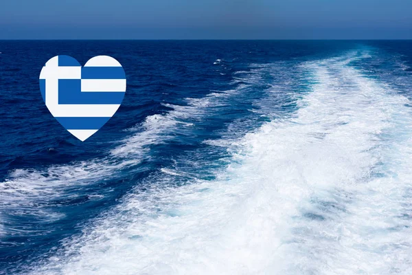 Heart shaped greek flag on background made of view of deep blue Mediterranian sea with kelvou jet, bubbles and waves