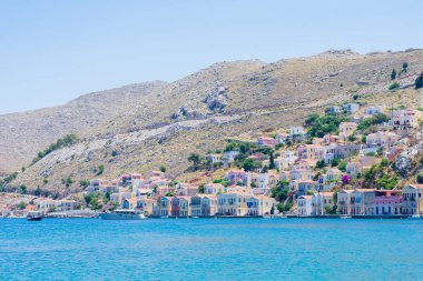 Yunan adasında güneşli bir yaz gününde, Akdeniz kıyısındaki kayalıklardaki küçük renkli evlerin manzarası, egzotik adalarda tatil.