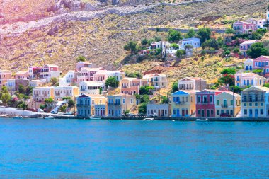 Akdeniz 'in kayalık sahillerinde güneşli yaz günlerinde Simy Yunan adasında bir sürü küçük renkli ev, egzotik adalarda turizm