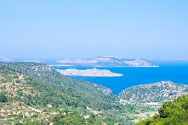 Güneşli yaz günlerinde Akdeniz, kayalar ve ağaçlarla dolu bir deniz manzarası. Yaz tatili