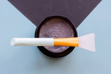 Yüz ve vücut için açık gri çamur maskesi kavanozu naneli ve siyah arka planda yumuşak fırçalı. Yüz bakımı ve tedavide kullanılan ev yapımı organik ürünler..