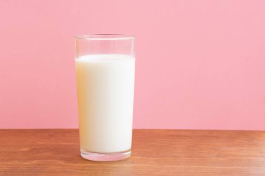 Ahşap masanın üzerinde bir bardak taze süt ve fotokopi alanı var. Tek nesne