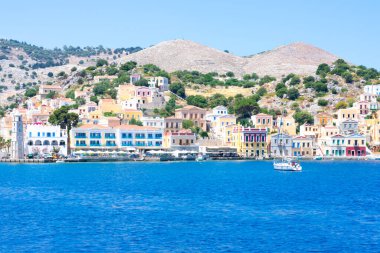 Akdeniz 'in kayalık sahillerinde güneşli yaz günlerinde Simy Yunan adasında bir sürü küçük renkli ev, egzotik adalarda turizm
