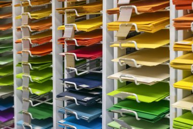 Rafta tasarım ve sanat için bir sürü renkli boş kağıt var. Dükkanda okul, kolej ve üniversite araçları olarak çok renkli çarşaf grubu. 