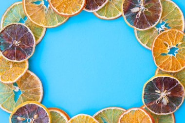 Limon, portakal ve mandalina olarak kurutulmuş sitruslardan oluşan yuvarlak çerçeve mavi zemin üzerinde kopyalanmış alandır. Kurumuş meyveleri olan tasarımcılar için sağlıklı beslenme kavramı olarak malzemeler
