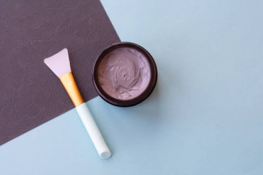 Yüz ve vücut için açık gri çamur maskesi kavanozu naneli ve siyah arka planda yumuşak fırçalı. Yüz bakımı ve tedavide kullanılan ev yapımı organik ürünler..