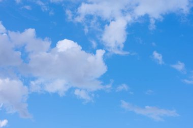 Bir sürü beyaz kabarık iplik bulutu ile mavi yaz gökyüzü. Bulutlu güneş ışığından yapılmış doğal arkaplan. 