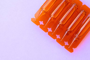 Mor arka planda enjeksiyon için ilaç verilmiş ampuller. Sağlık için sıvı ilaç içeren şeffaf kapsüller. İlaç endüstrisi..