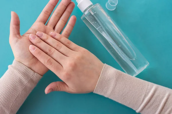 Ellerin antiseptik sıvıyla dolu sprey şişesi kullanışının üst görüntüsü. Sağlık, hijyen ve koronavirüsün yayılmasını önleme kavramı