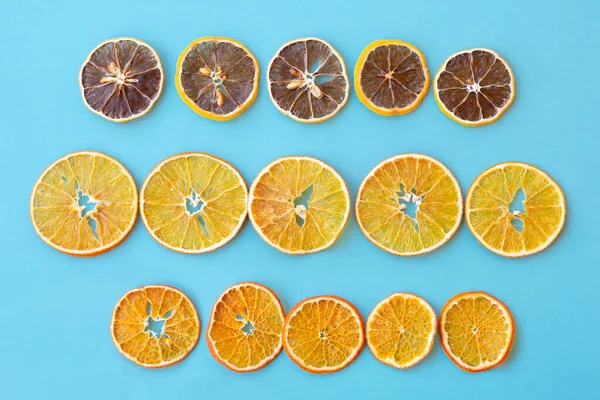Row of dehydrated citrus fruits as lemons, tangerines, oranges on blue background. Slices of dried citrus fruits.