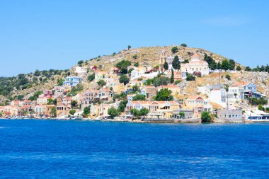 Akdeniz 'in kayalık sahillerinde güneşli yaz günlerinde Simy Yunan adasında bir sürü küçük renkli ev, egzotik adalarda turizm